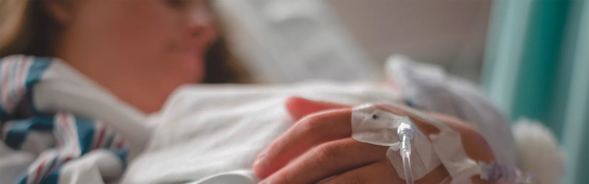 Patiente allongée à l'hôpital, main posée sur le drap