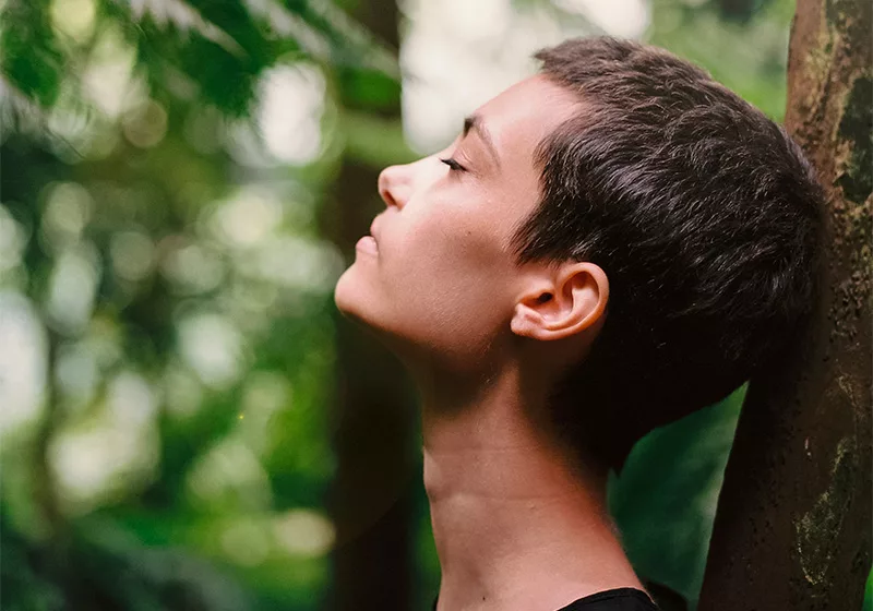 Femme les yeux fermés respirant dans la nature